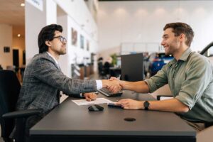 A couple reviews auto loan documents and compares monthly payment figures at a table.